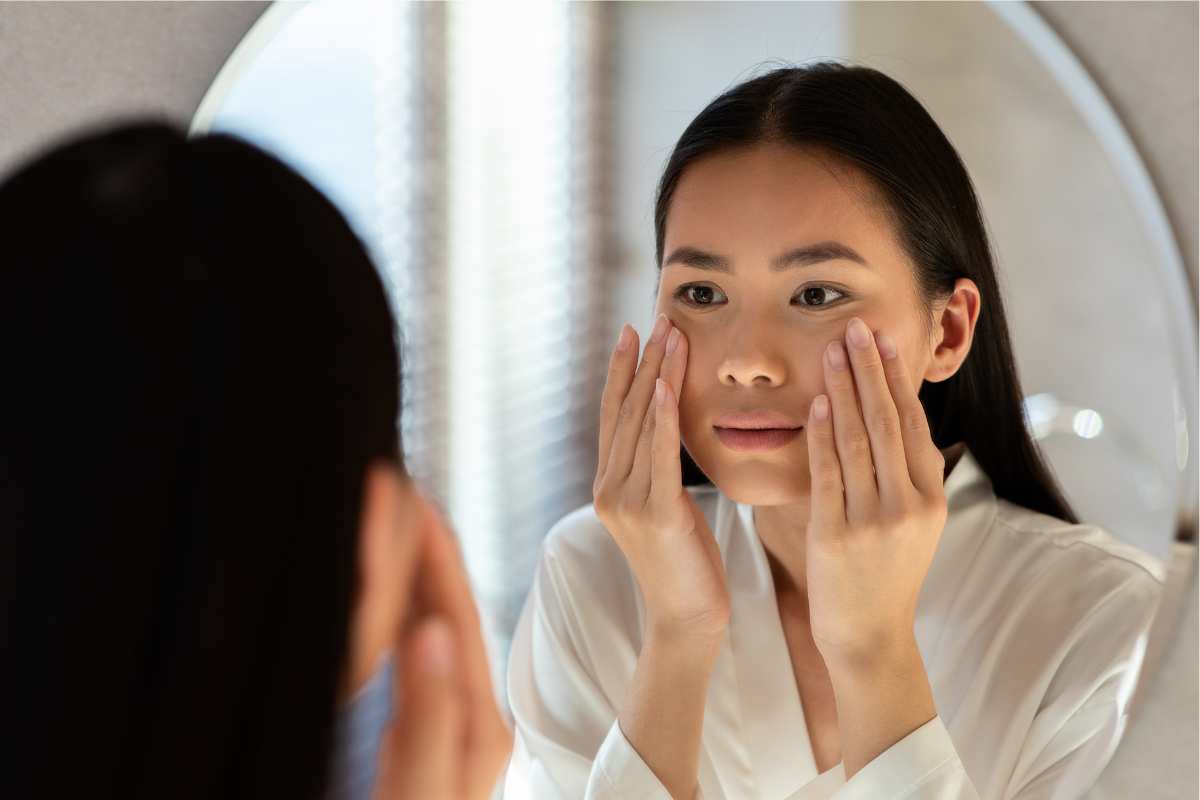 Woman examining her complexion while using a Sensitive Skin Pack for calming and repairing reactive skin