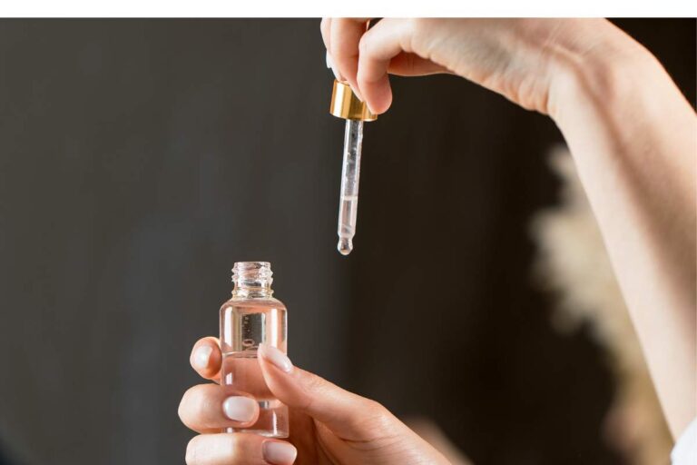 Hand holding a skincare serum dropper above a glass bottle, illustrating peptide therapy and precision application in an advanced skincare routine.