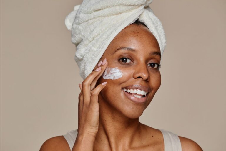Woman gently applying moisturiser to her cheek as part of a daily skin barrier repair skincare routine