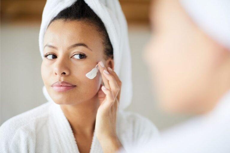 Woman applying skincare cream in the mirror as part of a consistent daily routine using skin repair products